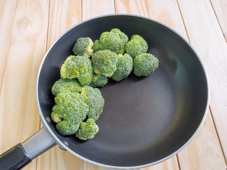 Fresh green broccoli on pan, wooden background