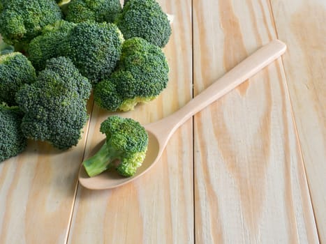 Fresh green broccoli with spoon on the wooden background