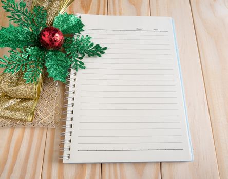 blank notebook with chrismas ribbon on wood background
