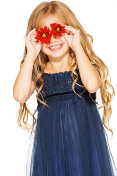 Little cute girl holding two red flowers near her eyes