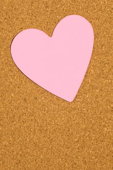 Blank pink heart shaped post it note stuck to bulletin board