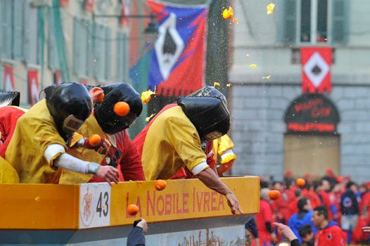ITALY, Ivrea: People in masks throw oranges from a float during the battle of oranges in Ivrea, Italy on February 8, 2016.This unique event sees people re-enact a middle age battle using oranges. Thousands gathered in the town to pelt each other with the fruit, which is imported from Sicily. 