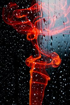 Smoke swirling on wet glass, black background
