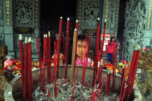 INDONESIA, Kuta: A child peers through a field of incense sprouting from a pit of ash at a temple in Kuta, Bali, Indonesia, as revelers celebrate the Lunar New Year on February 8, 2016. Others pray, dance, and light candles as they welcome the Year of the Monkey.