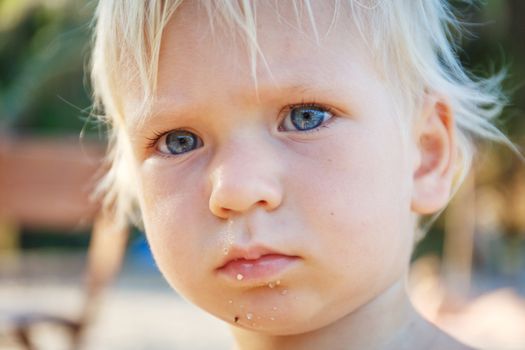 Baby with blond hair and blue eyes on the beach