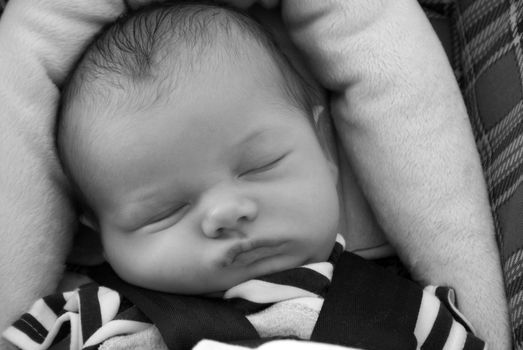 A newborn baby boy sleeps in his carseat.