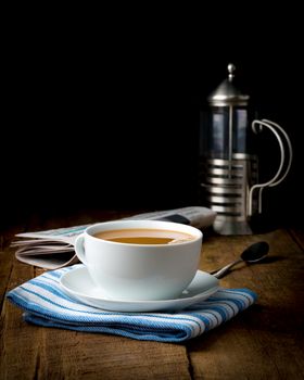 Cup of coffee with cream photographed on an artistic low key background.