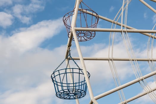 Part of Ferris wheel with blue sky in background.