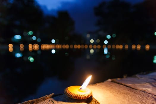 Little candle on ground beside pond.