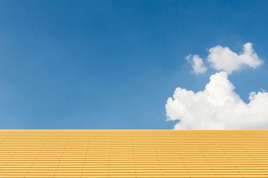 Yellow roof with clear sky and cloud in background.