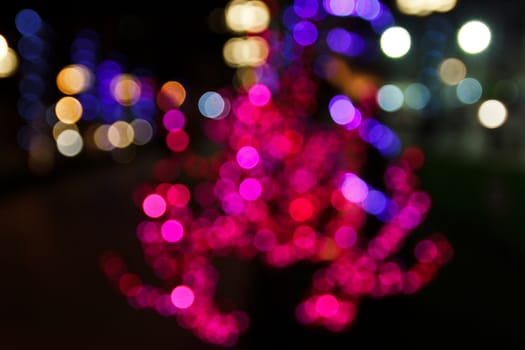 Bokeh of light on the tree at night along the road.