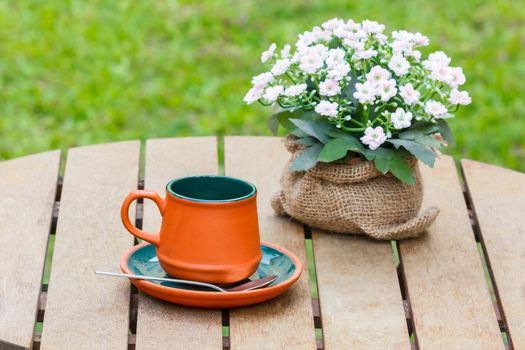 Clay cup with boquet of flower and grass in the background.
