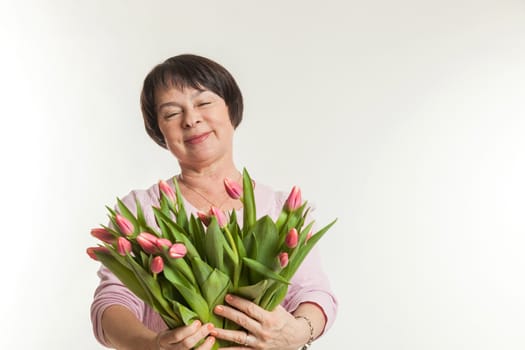 the beautiful mature woman admires to a bouquet of tulips