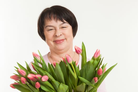 the beautiful mature woman admires to a bouquet of tulips