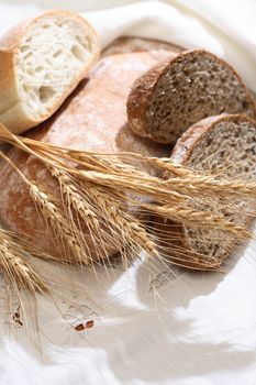 Farm still life. Freshness bread set on white tablecloth near wheat ears