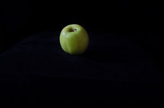 one green apple on a black background fresch and healty