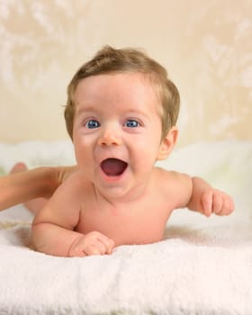 Cute infant boy lie prone and smiling.