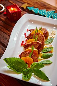 Grilled pork with mandarin oranges decorated with basil on a white plate