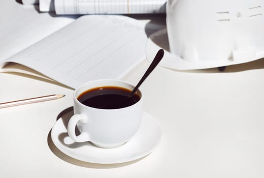 workplace architect. A cup of coffee, a helmet and blueprints on white table.