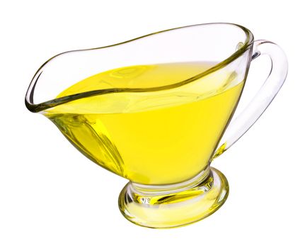 Glass gravy boat with yellow vegetable oil isolated on white background.