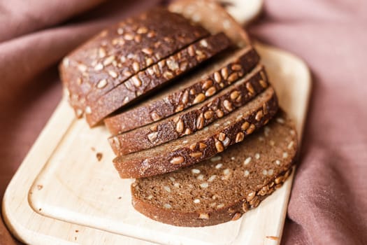 Sliced dark bread with crumbs on wood board