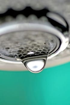 A macro of a white tap / faucet dripping with blue background.