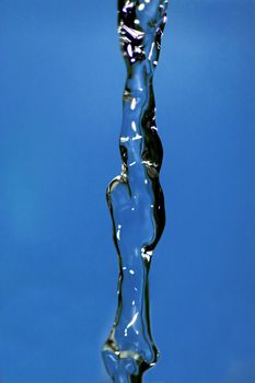 Water falling down, frozen in time with blue background.