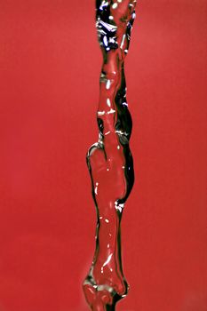 Water falling down, frozen in time with red background.