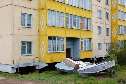 Boats at ground near apartment building, Chersky town,Yakutia, Russia