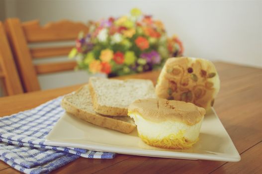 Cup cake with golden threads place in plate with bread on wood table with blue fabric vintage style.