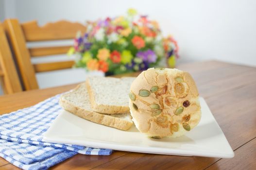 Cup cake with pumpkin seeds and currant place in plate with bread on wood table with blue fabric.