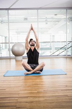 Handsome man doing yoga on mat in the studio