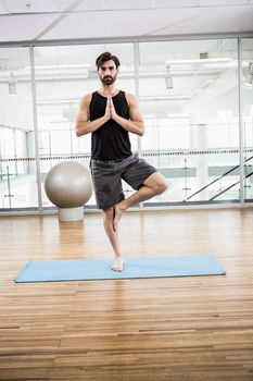 Handsome man doing yoga on mat in the studio