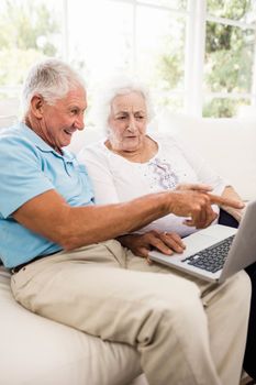Focused senior couple using laptop at home