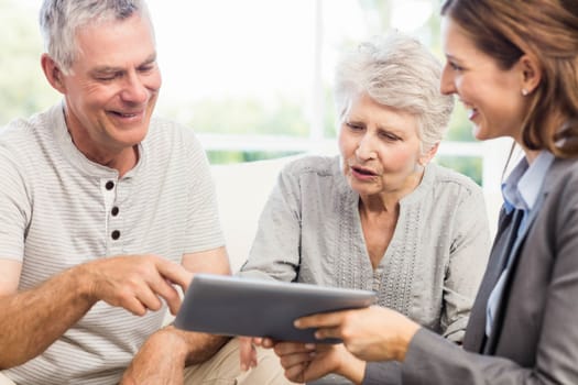 Businesswoman showing tablet to senior couple at home