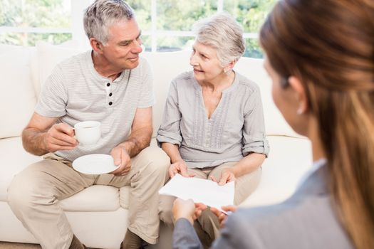 Businesswoman showing documents to senior couple at home