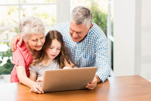 Grandparents and granddaughter using laptop at home