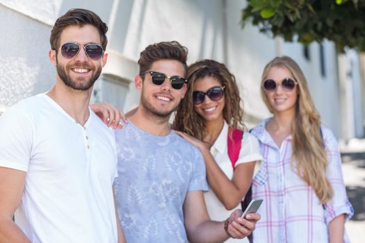 Hip friends looking at smartphone leaning against wall