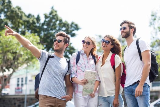 Hip friends holding map and pointing outdoors