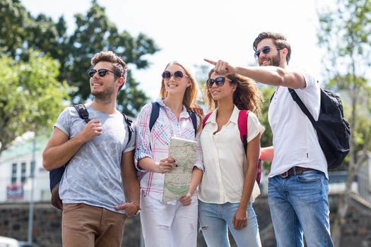 Hip friends holding map and pointing outdoors