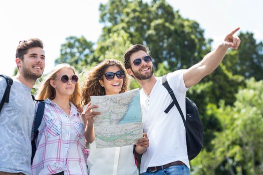 Hip friends holding map and pointing outdoors