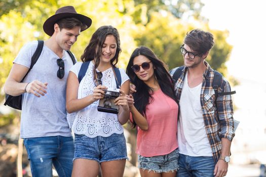 hip friends looking at digital camera outdoors