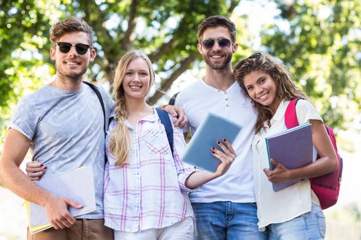 Hip friends holding tablet and notebooks outdoors