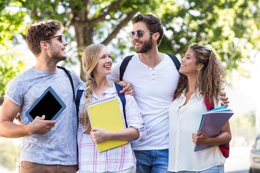 Hip friends holding notebooks and tablet outdoors