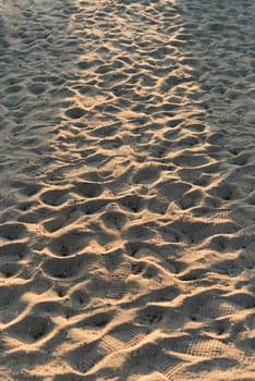 Closeup of sand pattern of a beach in the summer with sunrise beam