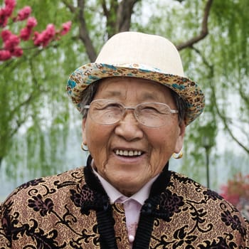 HANGZHOU, CHINA - April 13, 2011 : View in the mist of Xihu, the west lake in hangzhou china, this is image of  old woman wearing a hat and glasses, smiling brightly.