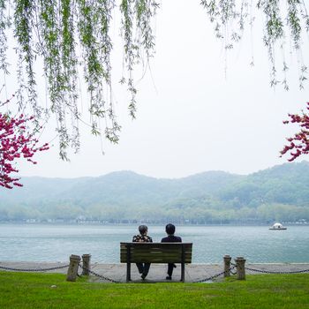HANGZHOU, CHINA - April 13, 2011 : View in the mist of Xihu, the west lake in hangzhou china, this is image of two Chinese old women sit on the bench by the lake