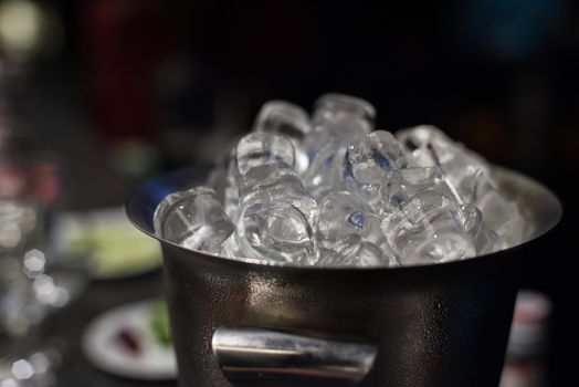 Ice bucket filled with ice cubes closeup