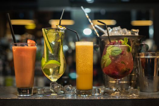 Glasses of different cocktails on bar background