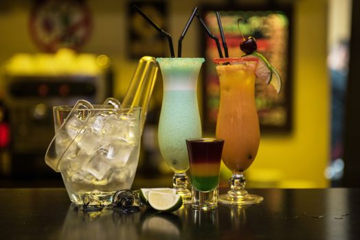 Glasses of different cocktails on bar background